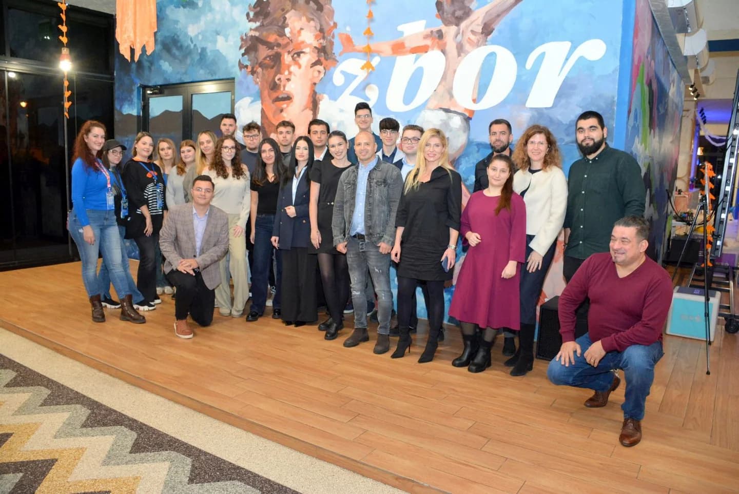 Fotografie de grup a participanților la Conectăm Viitorul, în fața picturii murale Zbor.